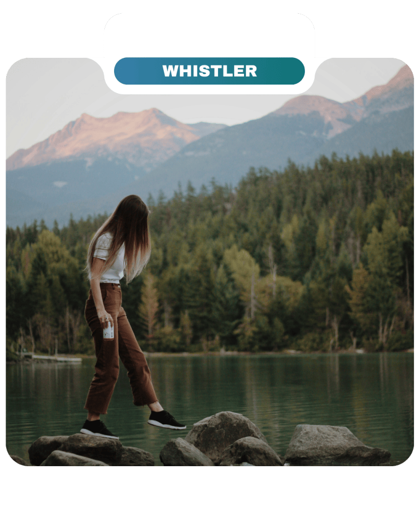 A person stands on rocks by a lake surrounded by trees and mountains, with a "Whistler" label at the top and a subtle nod to Lifty Life adventure in the fresh mountain air.