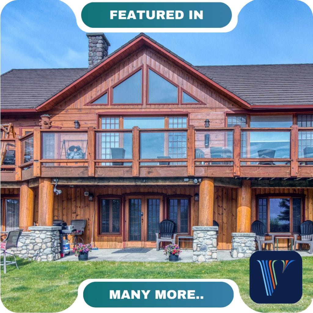 A two-story log cabin with large windows, a stone chimney, glass balcony railings, outdoor seating, and a well-maintained lawn. Text reads "FEATURED IN" with "MANY MORE PARTNERS...