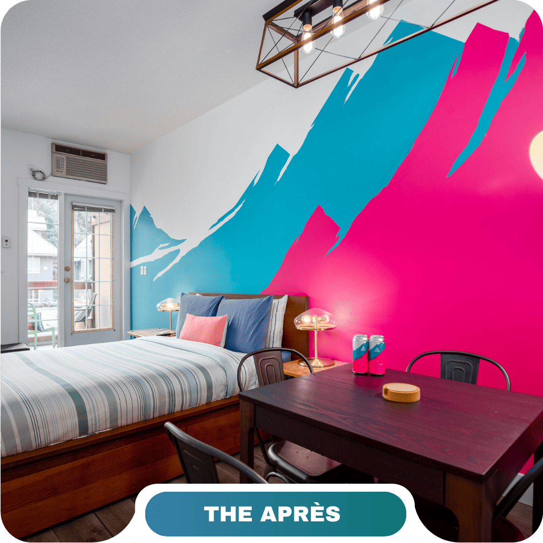A modern bedroom with a striped bed, wooden furniture, and a bold blue and pink mountain mural on the wall; "THE APRÈS" label at the bottom—perfect inspiration for vacation rentals in Whistler.